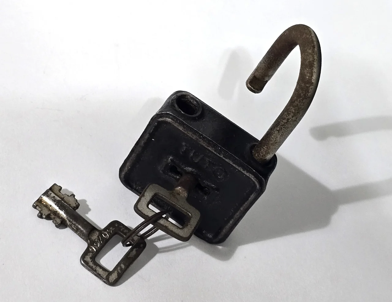 מנעול עתיק ממתכת, חתום TUTO, עם המפתח המקורי. מצב שימושי עם פטינה של הזמן. מידות: ‎8 × 4 × 2 ס”מ