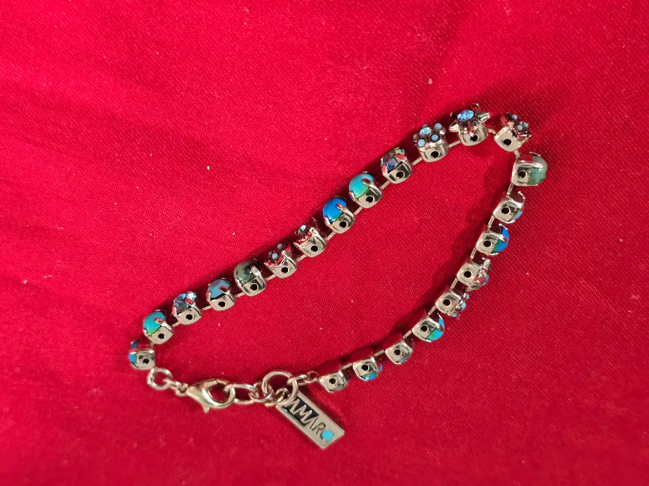 צמיד טניס וינט'ג של המותג אמארו (Amaro) עשוי מפליז בגימור מוזהב ומשובץ באבני תורכיז וקריסטלים בגווני כחול ותכלת