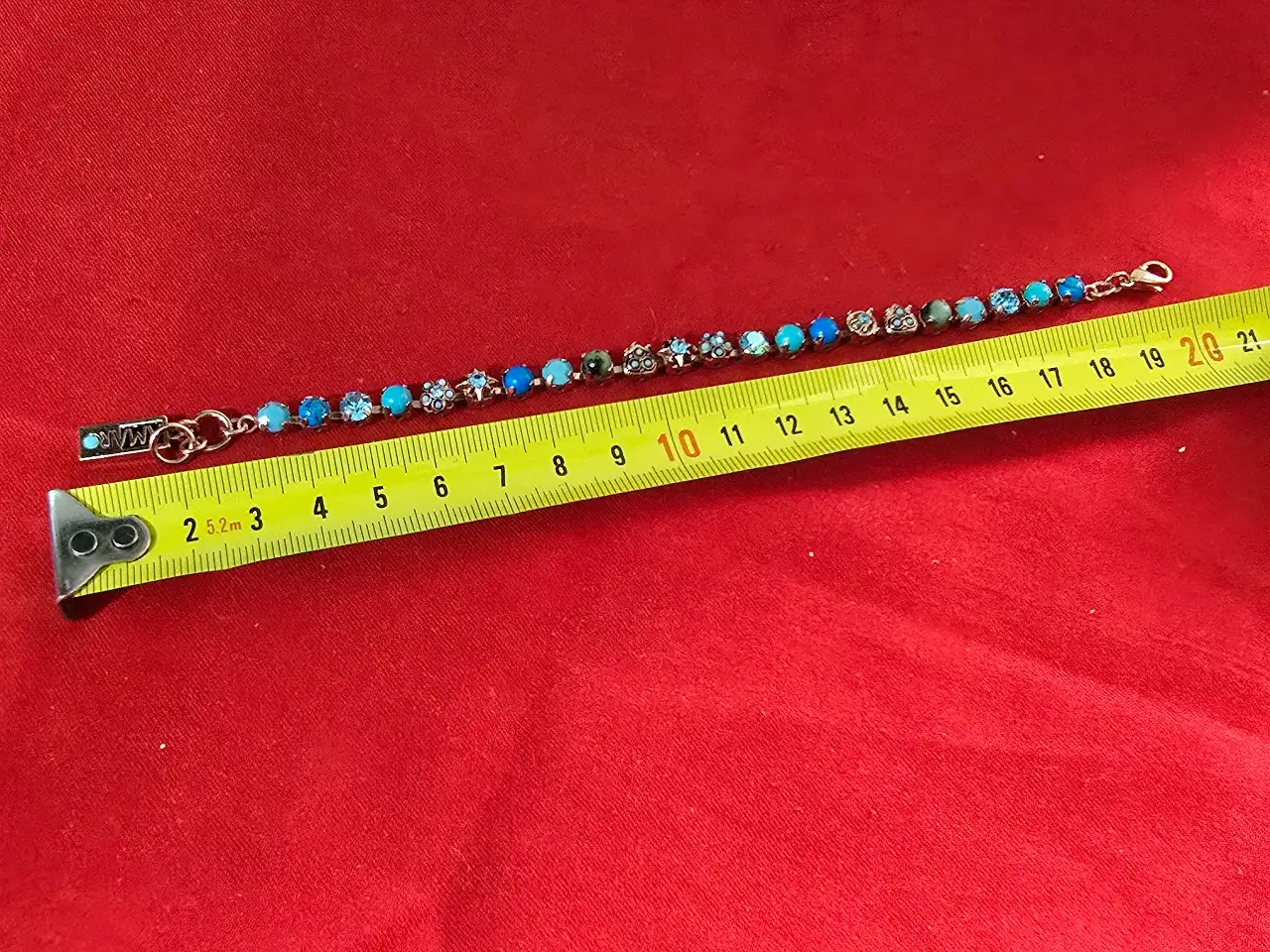 צמיד טניס וינט'ג של המותג אמארו (Amaro) עשוי מפליז בגימור מוזהב ומשובץ באבני תורכיז וקריסטלים בגווני כחול ותכלת