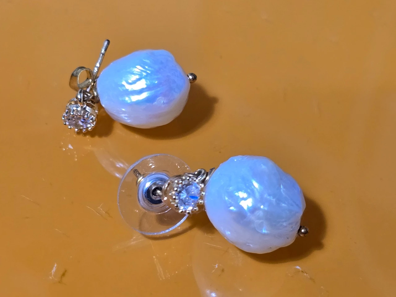 זוג עגילי פנינה טבעית בצורה לא סימטרית העגילים כוללים חלק עליון משובץ באבנים קטנות זרקונים