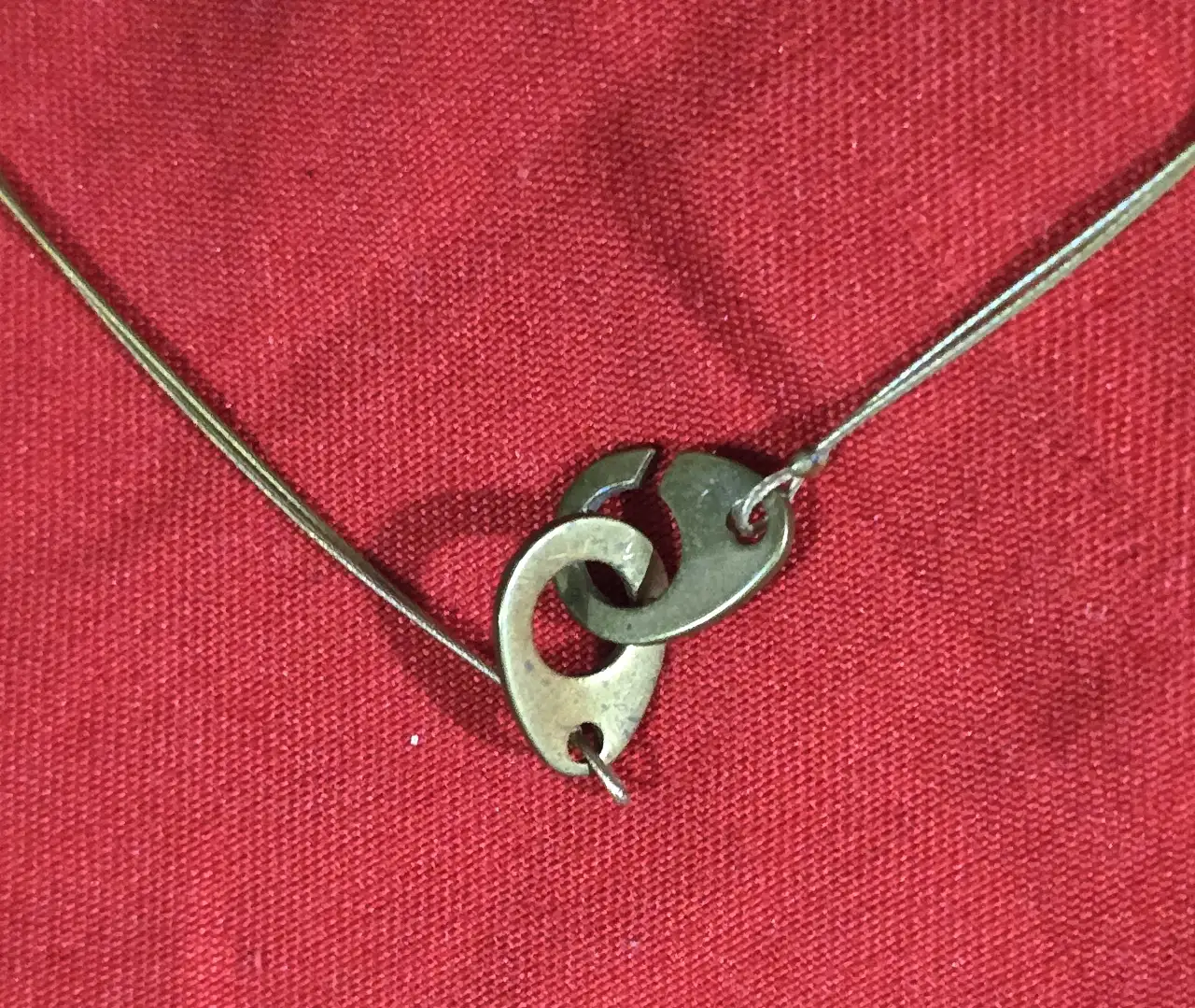 שרשרת קולר בעלת עיצוב מנימליסטי המורכבת מחישוק מתכת דק וחרוז מרכזי בגוון אדום