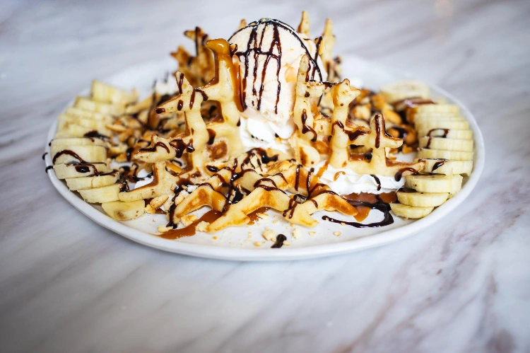 קרפ צרפתי בצלחת מוגש עם שני כדורי גלידה וקצפת