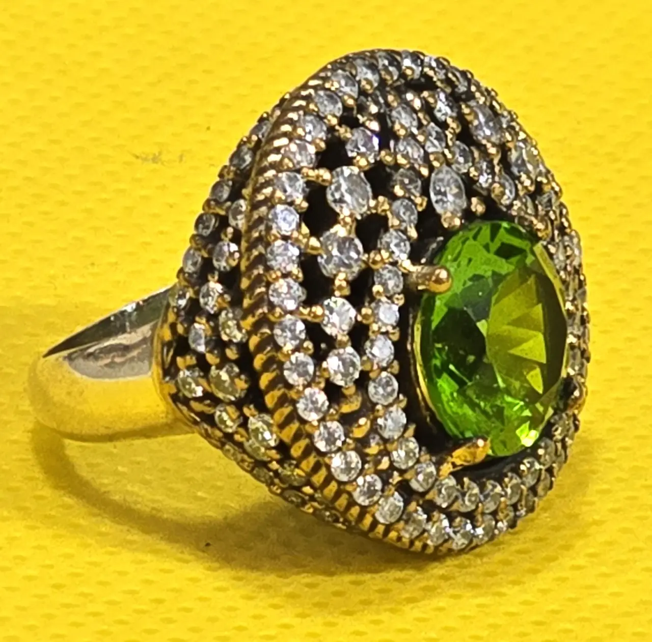 טבעת כסף 925 חתומה מידה 7\7.5 אבן מרכזית זו אבן פרידוט ומסביב אבני סברובסקי יש נגיעות של זהב