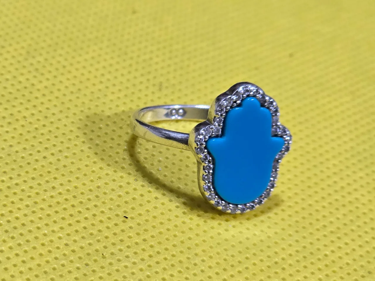 טבעת חמסה כסף 925 חתומה, משובצת טורקיז בליטוש חמסה ומסביב אבני זירקון עגולות קטנות.