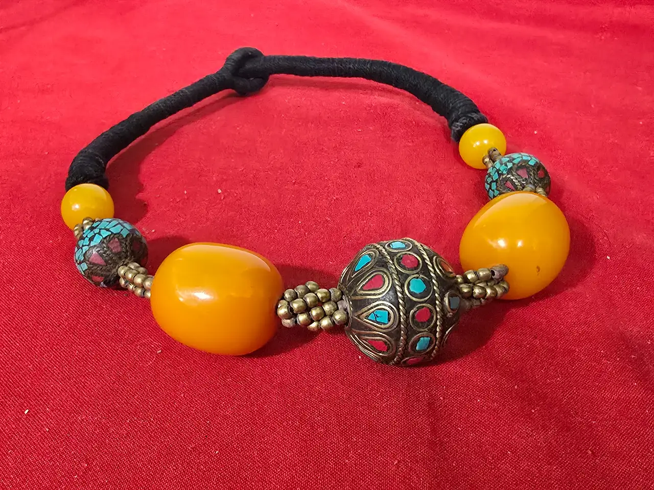 שרשרת בעלת מראה אתני אזור טיבט נפאל או מרכז אסיה החרוזים בגוון צהוב הם חרוזיח ענבר בנוסף אבני טורקיז התכשיט מושחל על שרוך בד שחור