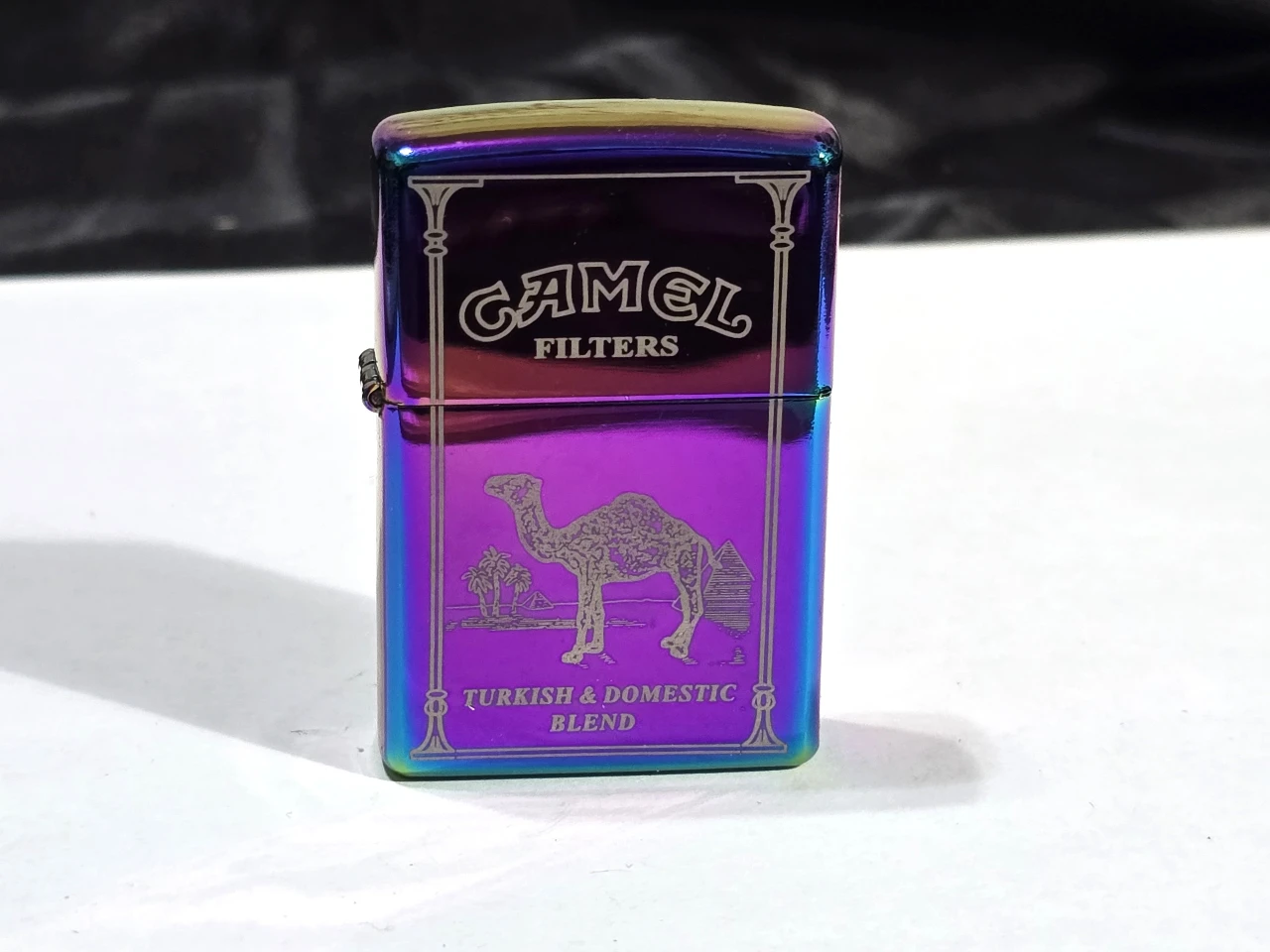 מצית כמו פעם ממותג CAMEL - מנגנון הצתה מכני. המיכל ריק - יש להוסיף בנזין למצתים לצורך הפעלה.  גובה 6 ס"מ, רוחב 4 ס"מ.
