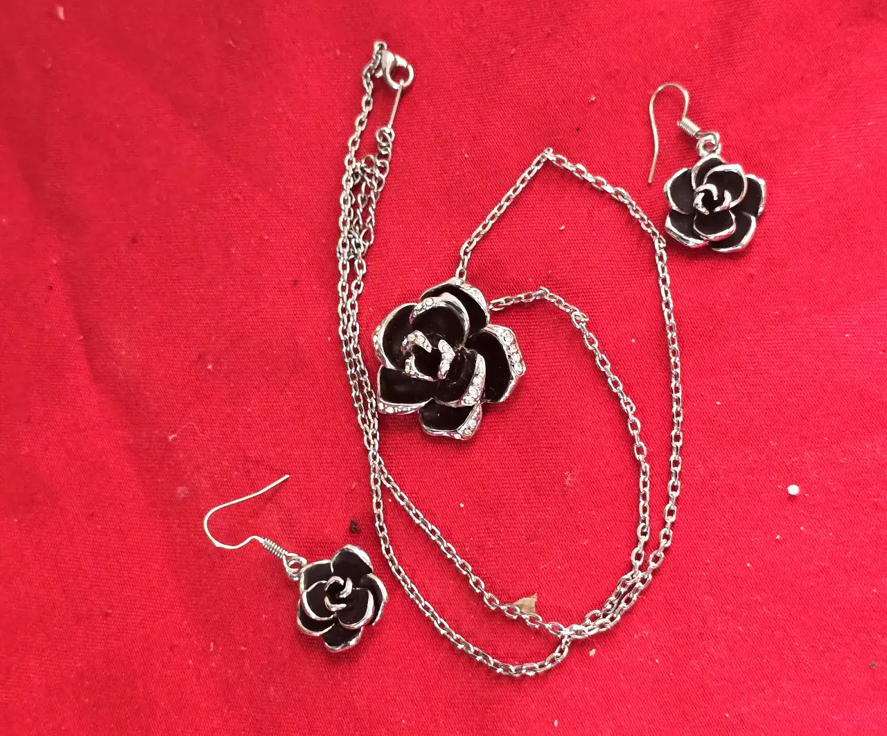 סט תכשטיםאלגנטי ותואם התליון במרכז שושנה עם תחושת עומק צבע שחור כנראה אמייל והעגילים תואמים לשרשרת