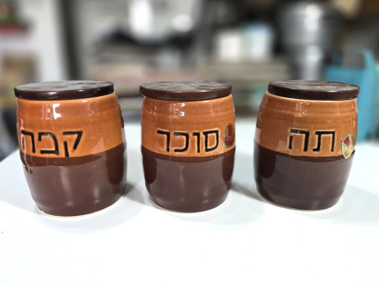 סט 3 מיכלי קרמיקה לסוכר, קפה ותה, עם מכסים מעץ, מידות 10/13 ס"מ  חתומים בבסיס ונושאים את מדבקת היצרן, בן פורת,  לא היו בשימוש.