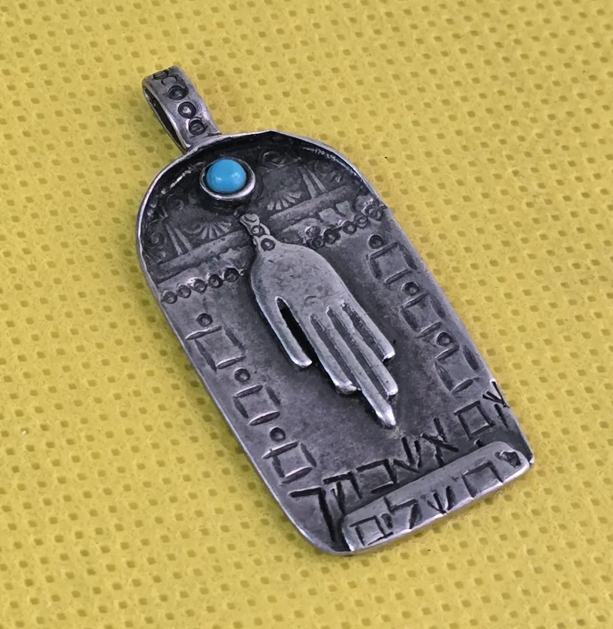 תליון קמע חמסה מכסף 925 חתום עבודת יד עם חרוז טורקיז חתום מאחור. מידה 4 על 2 סמ הכיתוב על התליון.....אם אשכחך ירושלים........