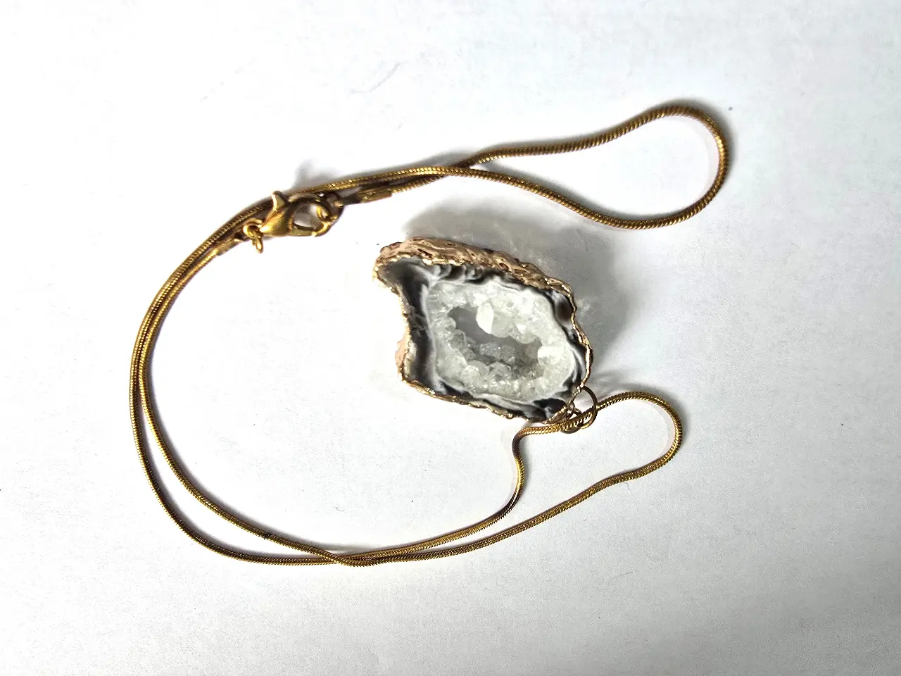 שרשרת זהובה עם תליון המורכב מאבן קריסטל גולמית האבן נתונה במסגרת מוזהבת