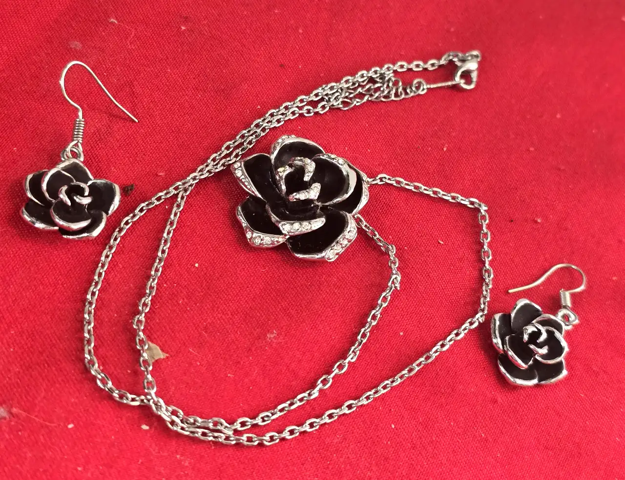 סט תכשטיםאלגנטי ותואם התליון במרכז שושנה עם תחושת עומק צבע שחור כנראה אמייל והעגילים תואמים לשרשרת