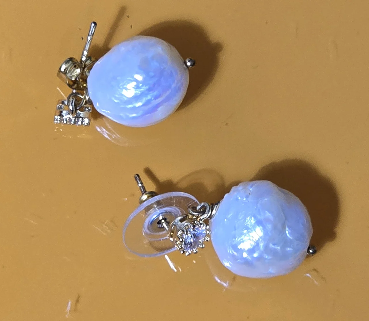 זוג עגילי פנינה טבעית בצורה לא סימטרית העגילים כוללים חלק עליון משובץ באבנים קטנות זרקונים