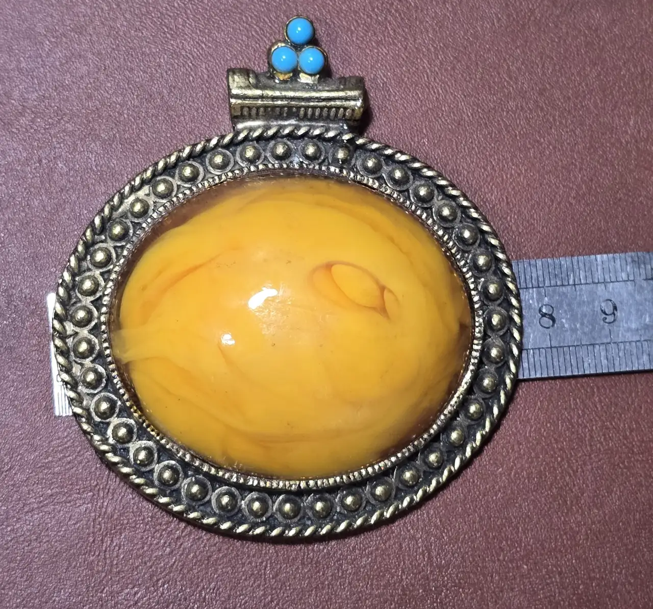 תליון גדול דמוי ענבר אובלי ו 3 אבני טורקיז משובצים על בסיס מתכת . 8.5×7.5×2.5 ס"מ