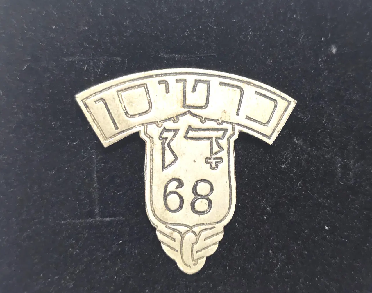 סמל כובע מוקדם כרטיסן בחברת האוטובוסים דן משנות ה-40. פלדה. מספר 68. מידות כ 32x32 מ״מ
