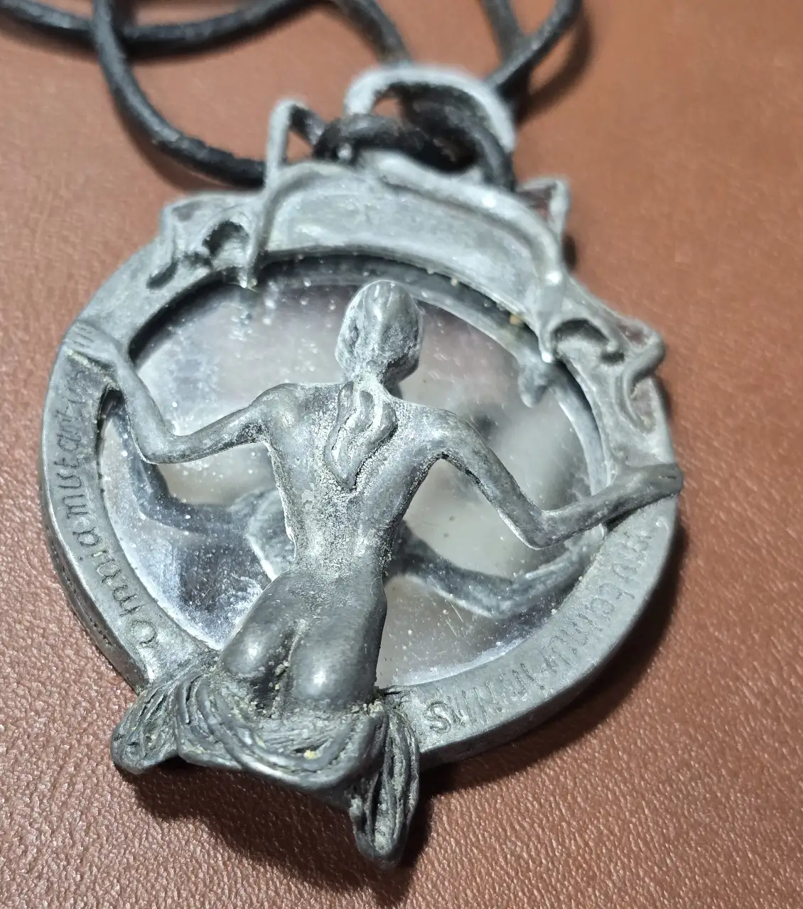 תליון מראה דמות נשית מביטה אל תוך המראה עשוי מפיוטר והדמות השניה מלאך המוות