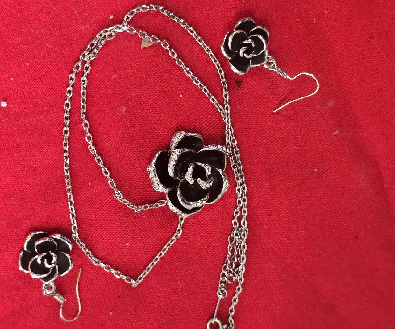 סט תכשטיםאלגנטי ותואם התליון במרכז שושנה עם תחושת עומק צבע שחור כנראה אמייל והעגילים תואמים לשרשרת