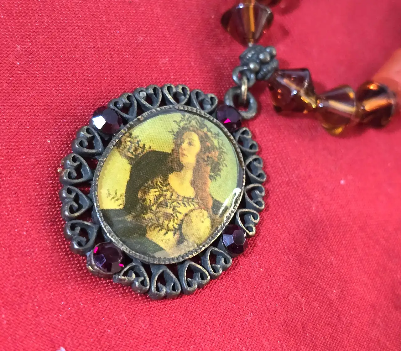 שרשרת בסגנון עתיק עם תליון המציג דמות נסיכה עשויה מחרוזי אלמוג אדומים בצורת גליל וחרוזי גראנט כהים יותר שמפרידים בינהים