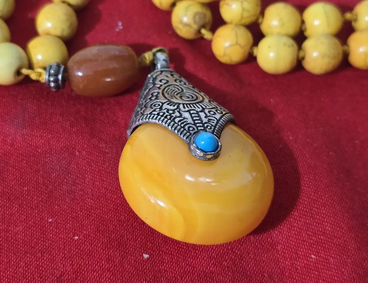 שרשרת חרוזים צהובה הכוללת 108 חרוזים משמשת בבודהיזים ובהינדונזים לספיר אורך המחרוזת 50 ס'מה לתפילה החרוזים אבן עינבר או חרוזי כורכום כולל גם תליון גדול אם אלמנט של כסף טיבטי