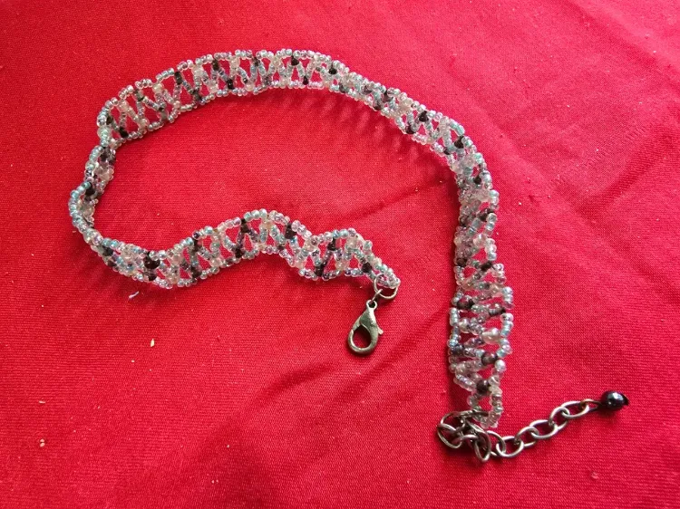 שרשרת בסגנון צ'וקר (Choker) או שרשרת קולר עשויה בעבודת יד חרוזי ונציה קטנים בגוון לבן שחור ואדום התכשיט מאופיין בדוגמת אריגה