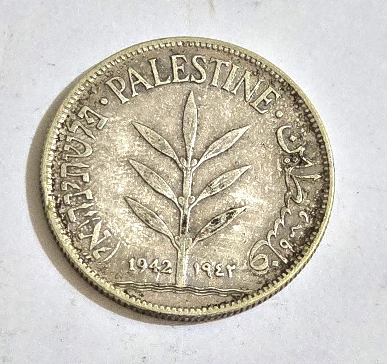 פלשתינה (א"י), 100 מיל 1942 - מטבע עשוי כסף 0.720, הנמנה על הסדרה היוקרתית של מטבעות 100 מיל, ששימשו הילך חוקי בתקופת המנדט הבריטי בפלשתינה, הלא היא ארץ ישראל.