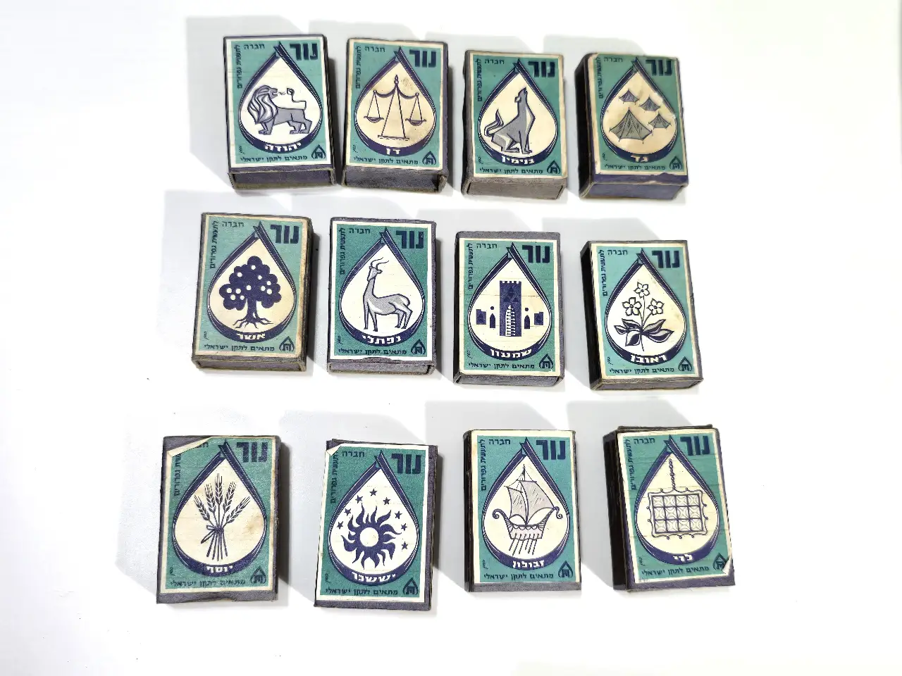 12 השבטים - לוט 12 קופסאות גפרורים ישראליות תוצרת "נור" סט 12 השבטים של ישראל ברקע תכלת-טורקיזי, בלאי קל, מעט גפרורים בחלק מהן.