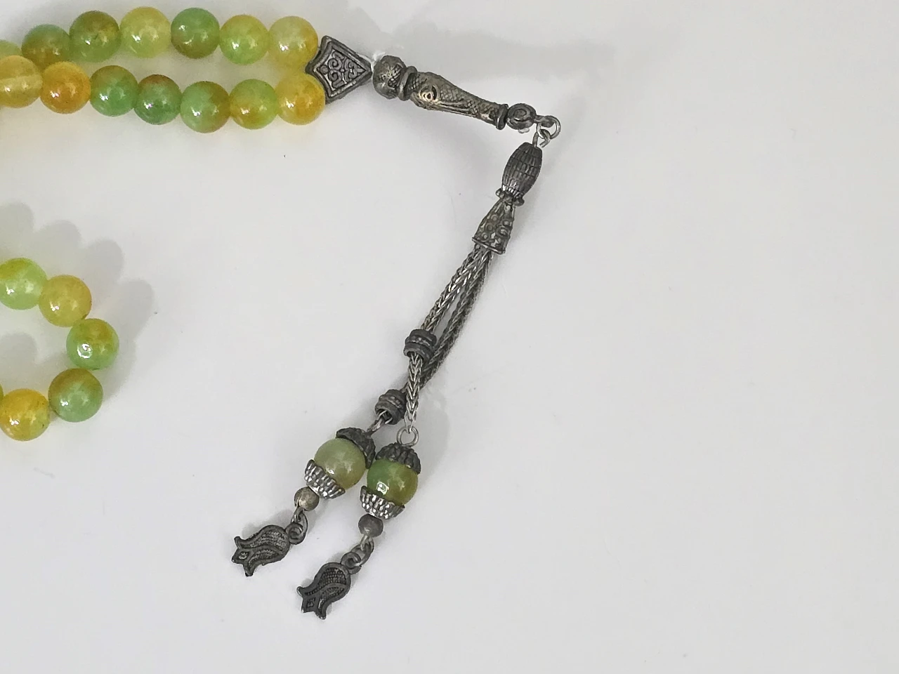 מסבחה תפילה איסלאמית ישנה, מורכבת מ-33 חרוזי זכוכית עגולים בגוונים ירוק-צהוב, משולבת חלקי מתכת בקצה, אורך כולל: 25 ס"מ, קוטר כל חרוז: 6 מ"מ, משקל כולל: 35 גר'.