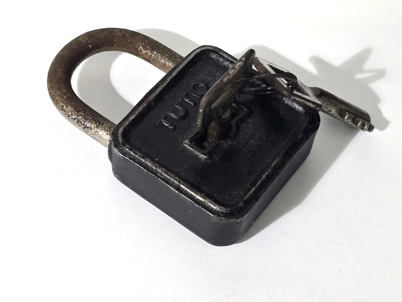 מנעול עתיק ממתכת, חתום TUTO, עם המפתח המקורי. מצב שימושי עם פטינה של הזמן. מידות: ‎8 × 4 × 2 ס”מ