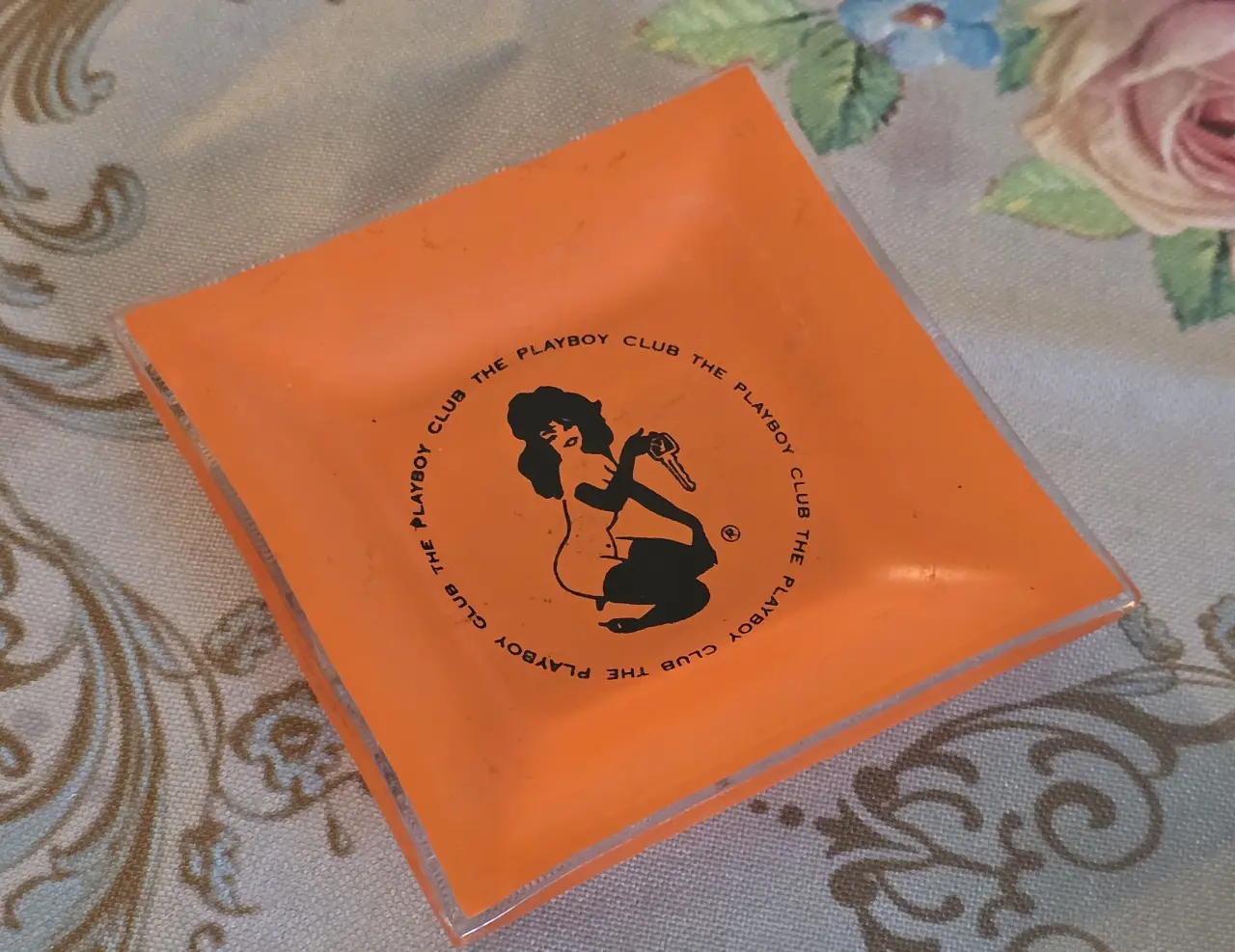 מאפרת זכוכית כתומה וינטג' "The Playboy Club", הדפס דמות ארנבונת המחזיקה מפתח – פריט אספנות רטרו מידות: 	9.5 x 9.5 ס"מ