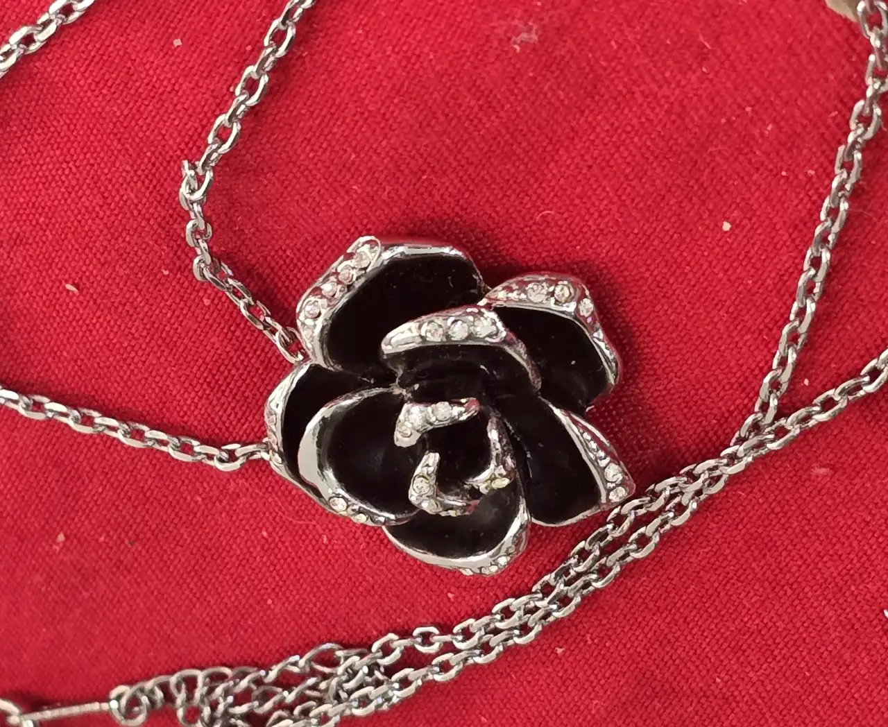 סט תכשטיםאלגנטי ותואם התליון במרכז שושנה עם תחושת עומק צבע שחור כנראה אמייל והעגילים תואמים לשרשרת