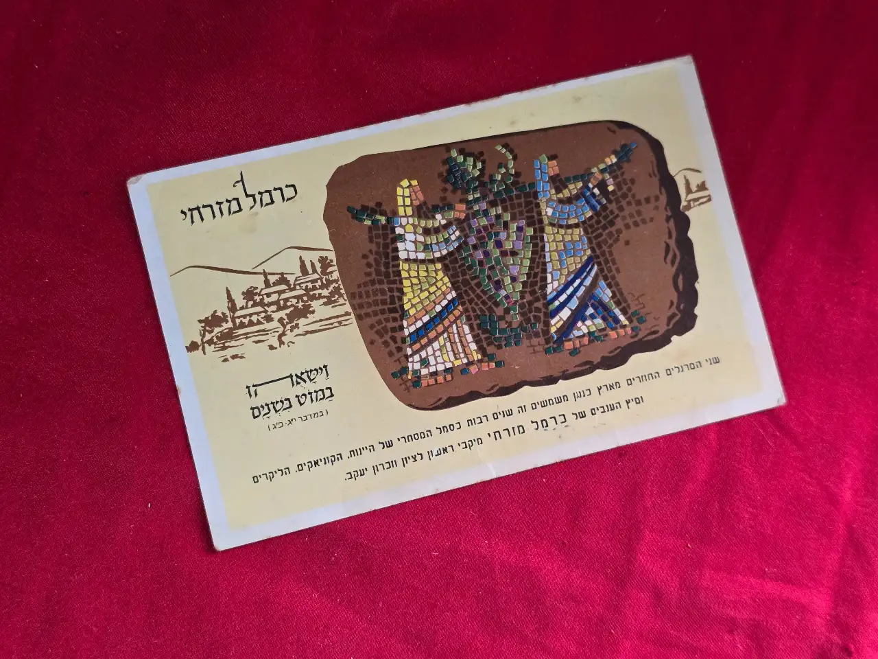 גלוית פרסומת של חברת המשקאות "כרמל מזרחי".  בחזית איור של שני המרגלים השבים מלתור את ארץ כנען.  "וישאוהו במוט בשנים" (במדבר, יג, כג).  מאחור: "שיר המזג".  משנות ה-60 של המאה הקודמת