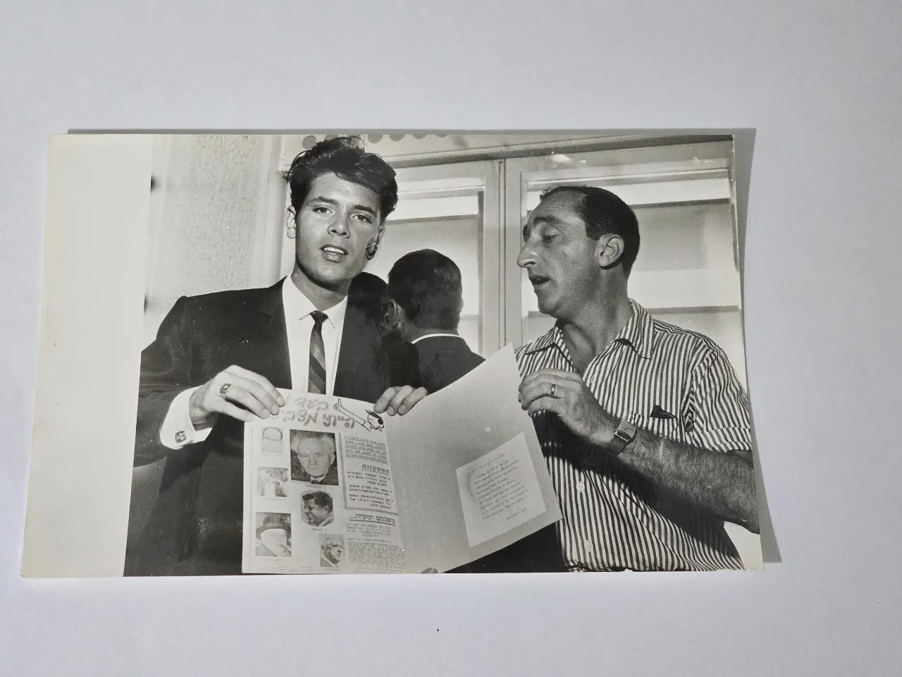 תצלום של הזמר קליף ריצ'רד בביקורו בישראל ב-1963, בחברת המפיק גיורא גודיק. תצלום חתום: נחום גוטמן מידות: 18 ס"מ * 12 ס"מ