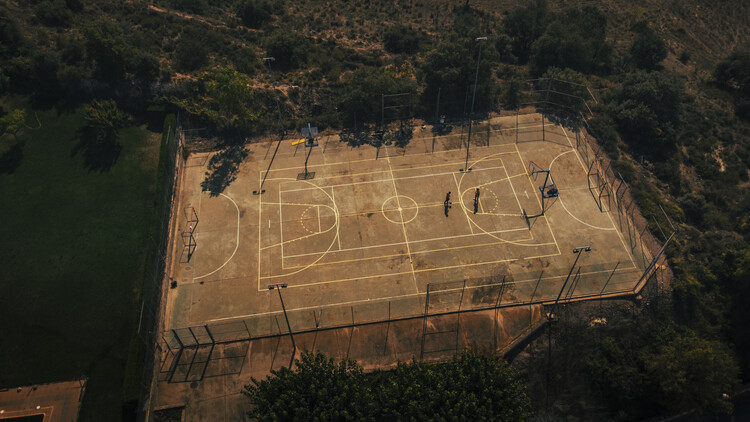 Photographie artistique Aerial shot of two friends playing basketball on a court during sunset