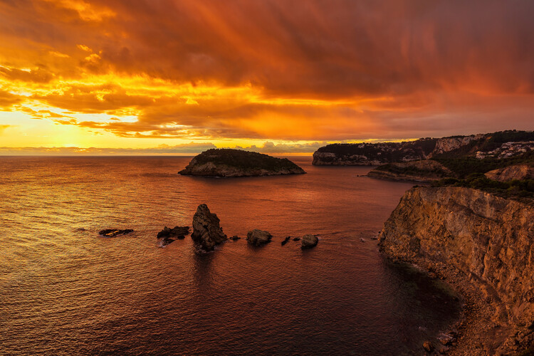 Художня фотографія A reddish sunrise next to the cliffs in the sea