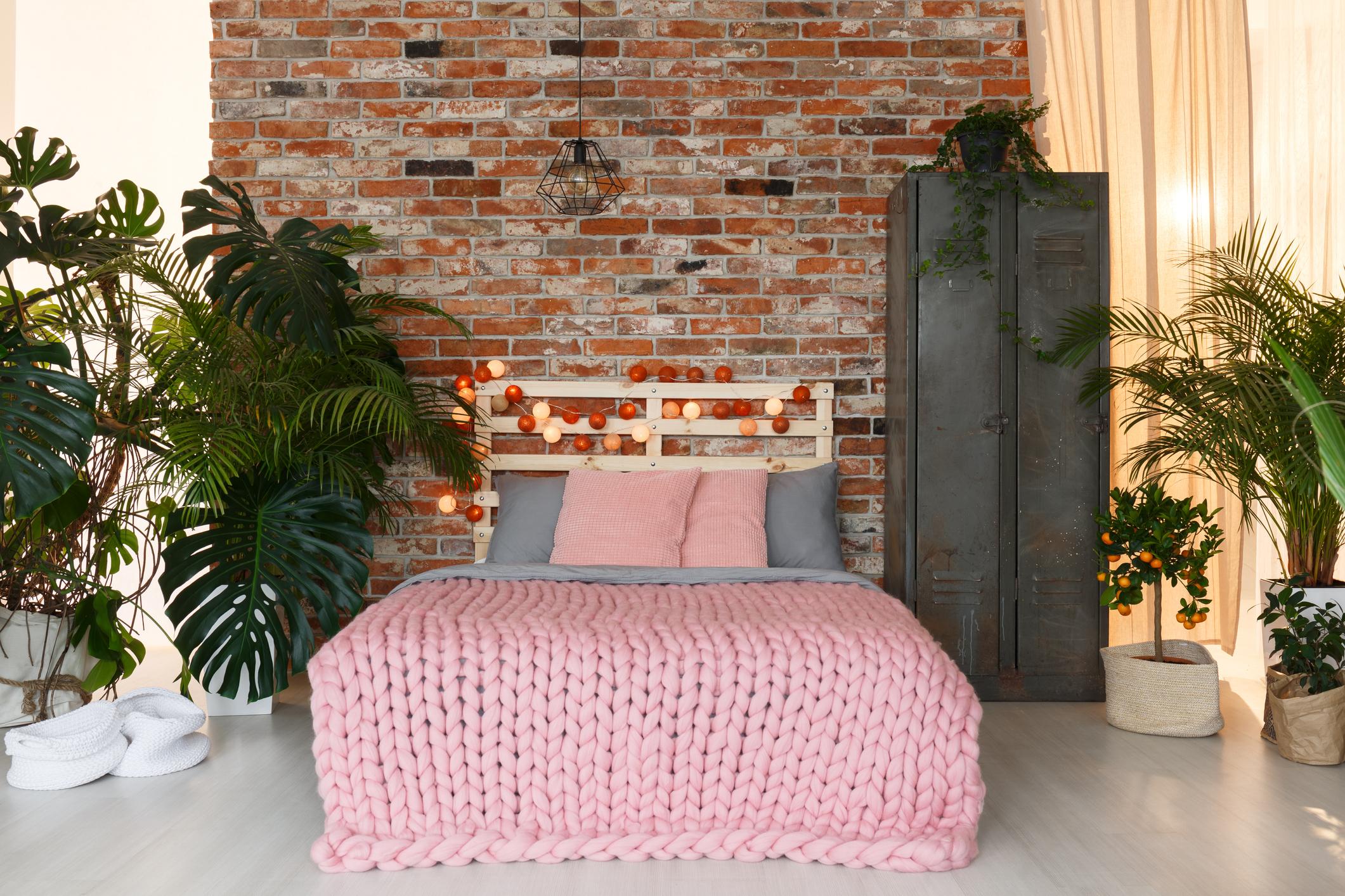 Manželská posteľ s ružovou dekou v industriálnej spálni
