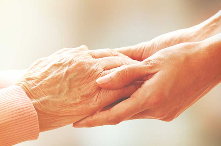 Caretaker holding hands of senior woman