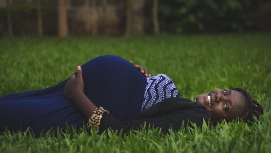 pregnant woman smiling lying in grass