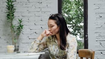 woman thinking at cafe table with laptop