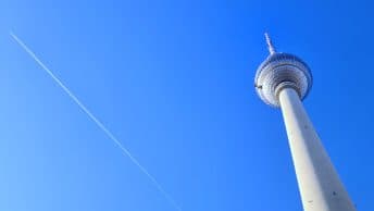 The TV tower in Berlin with an airplane behind it