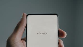 A phone in someone's hand that says hello world