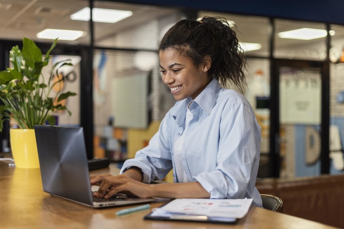 Mulher negra trabalha sorridente no computador