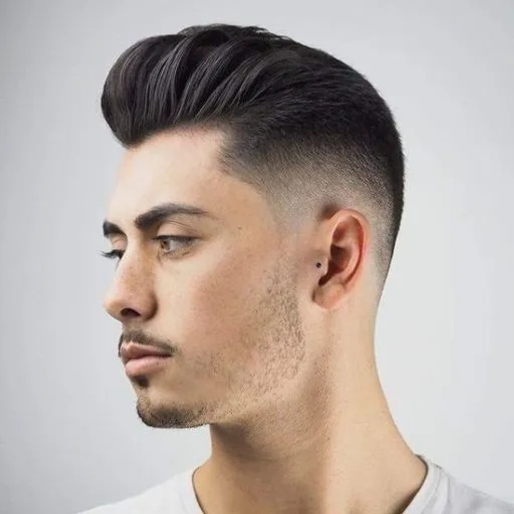 Young white guy with a pompadour hairstyle dressed in black shirt with a  serious face on brick wall background - Stock Image - Everypixel