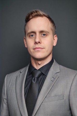 Young man with short hair poses for a studio headshot