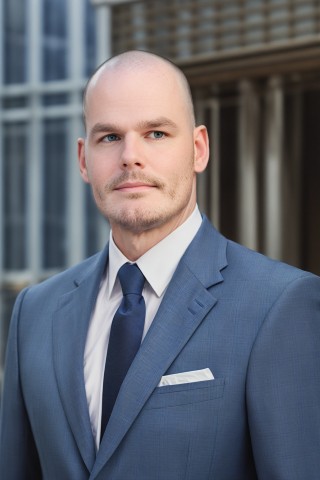 Man with blue eyes wearing a blue suit in front of a business building