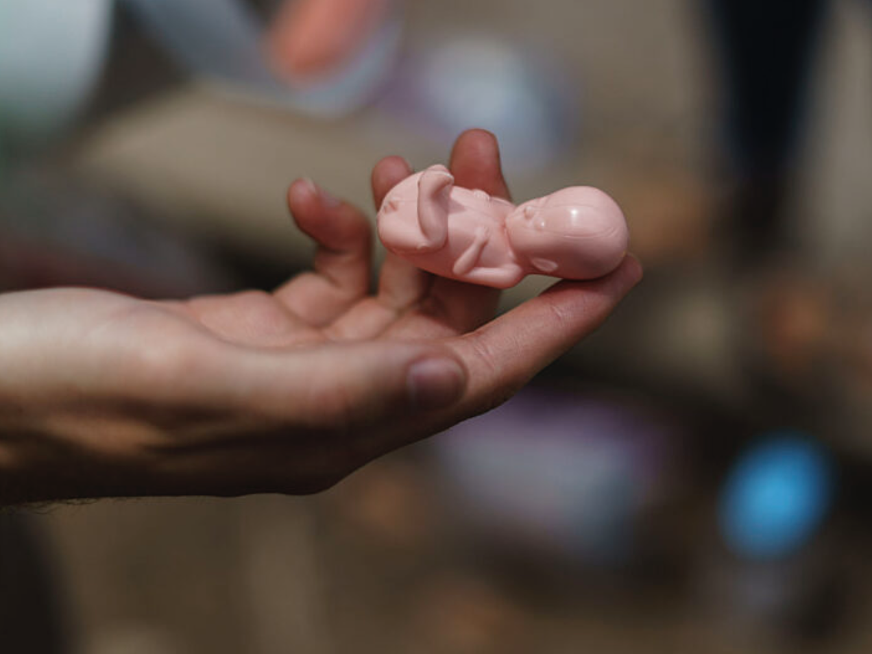 Hand holding tiny newborn doll