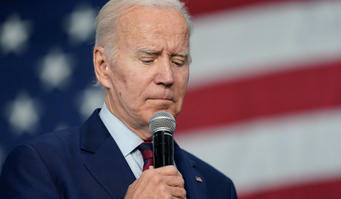 Biden looking down flag behind him