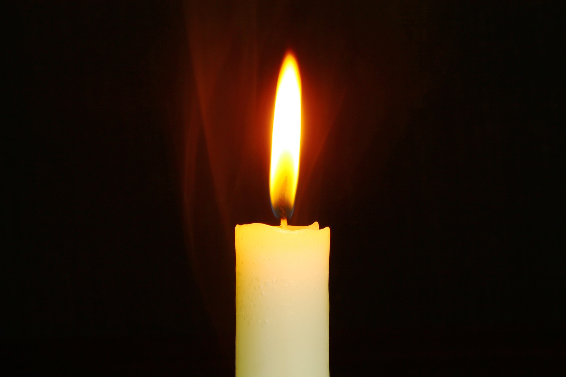 Lit candle on black background