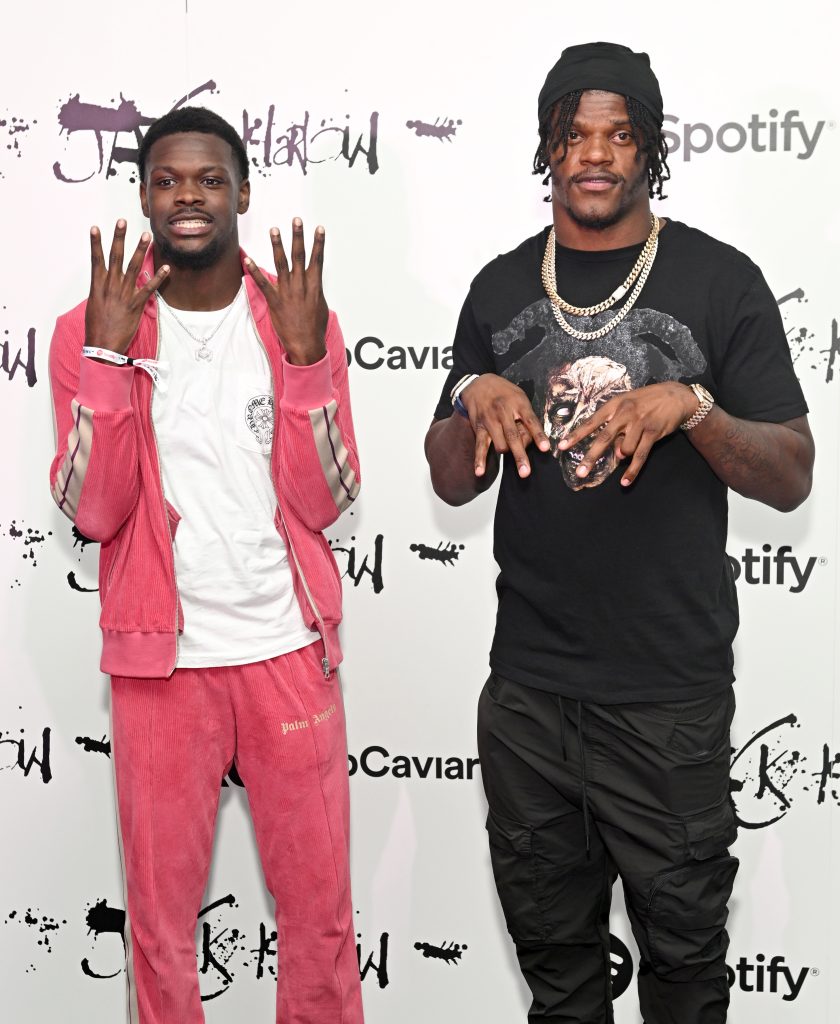 Malik Cunningham and Lamar Jackson posing in front of a Spotify x Rap Caviar step-and-repeat.