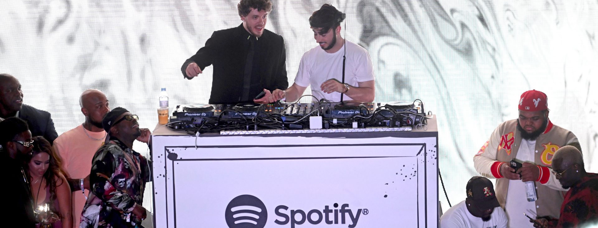 Jack Harlow and Zack Bia dancing and singing along to music at the DJ booth.