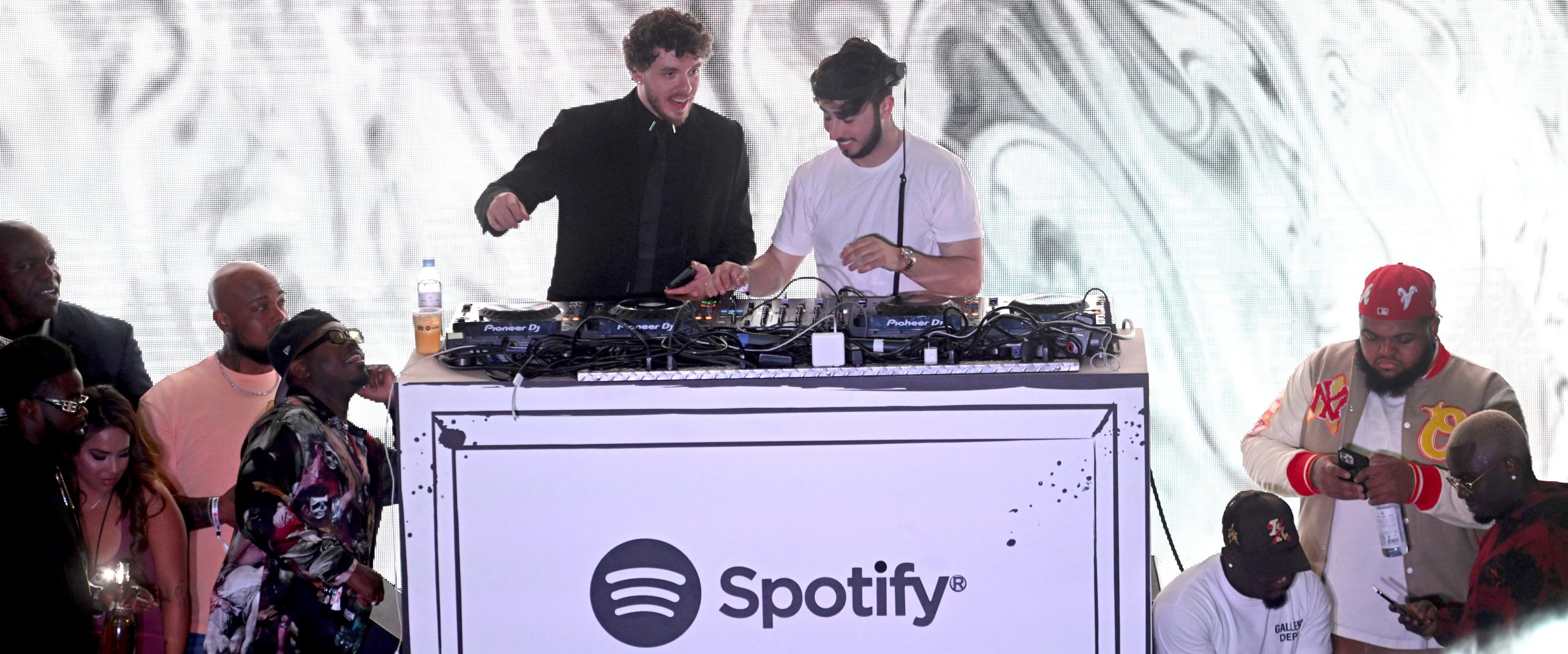 Jack Harlow and Zack Bia dancing and singing along to music at the DJ booth.