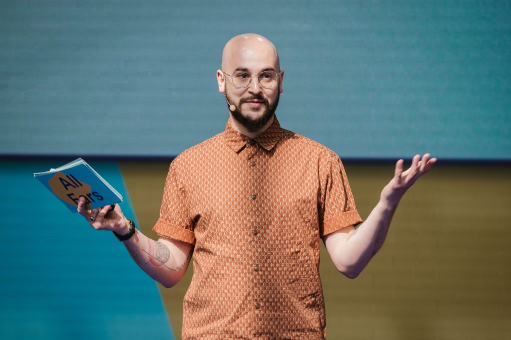 Daniel Nikolaou, Content Development Lead at Spotify is standing on the stage at the Spotify All Ears Summit talking to the audience